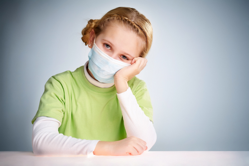 A little girl sitting in protective mask